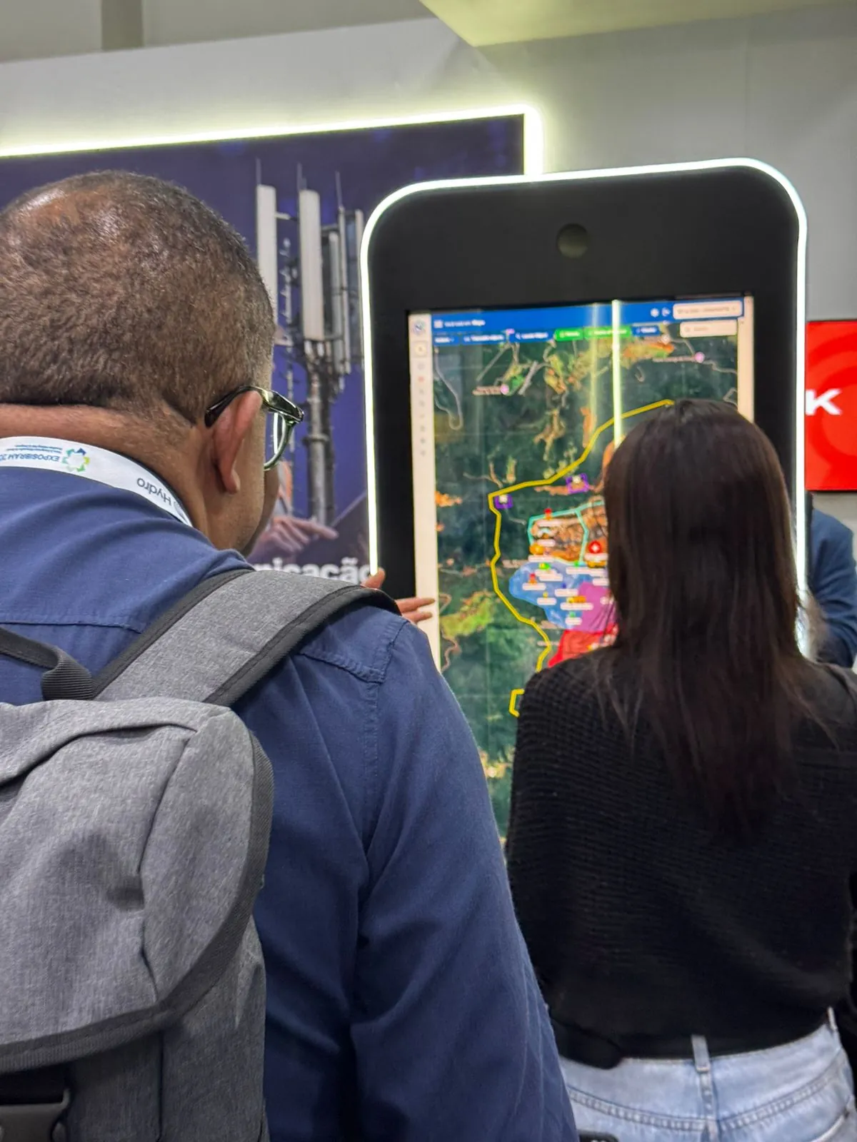 Visitantes interagindo com totem de mapa em feira